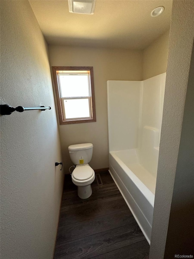 bathroom with a bathing tub, hardwood / wood-style floors, and toilet