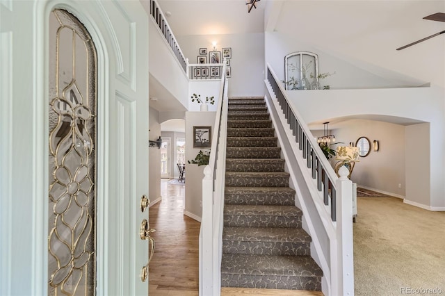 foyer entrance with hardwood / wood-style floors and ceiling fan with notable chandelier