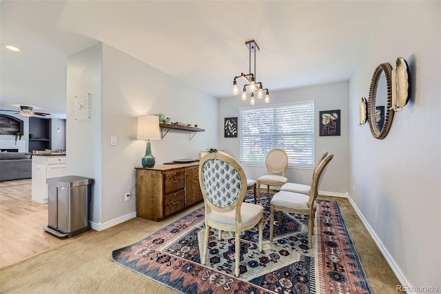 dining space featuring light colored carpet and ceiling fan with notable chandelier