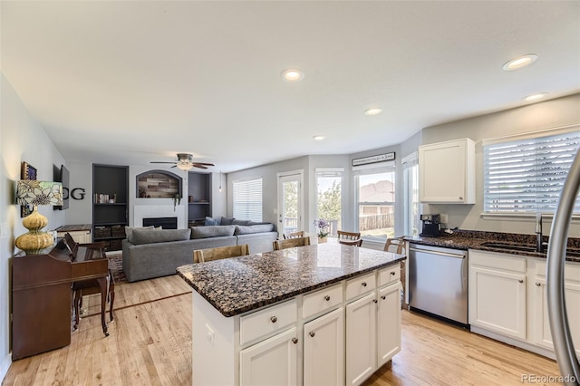 kitchen with dishwasher, white cabinets, a fireplace, and light hardwood / wood-style floors