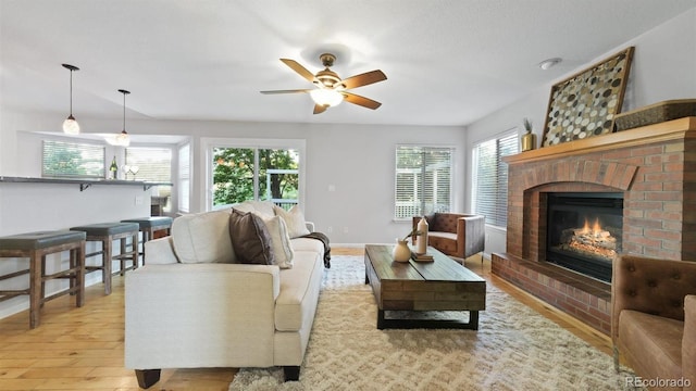 5150 Morning Glory Pl, Highlands Ranch, CO 80130 - living area featuring light wood finished floors, a brick fireplace, and a ceiling fan