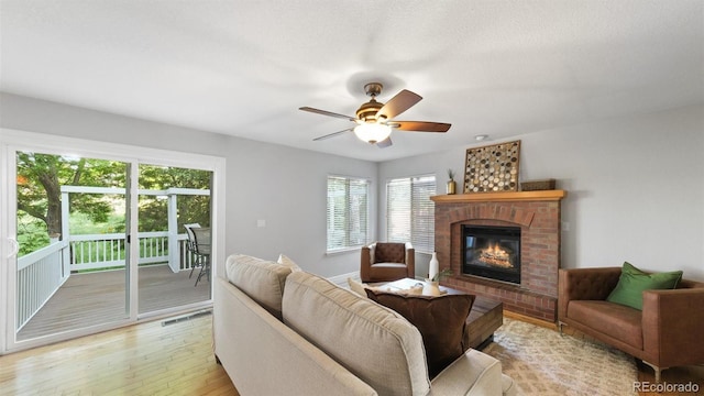 5150 Morning Glory Pl, Highlands Ranch, CO 80130 - living room with light wood-style flooring, plenty of natural light, a brick fireplace, and ceiling fan