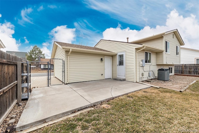 rear view of house with a patio, central air condition unit, fence, a lawn, and a gate