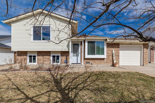 split level home featuring a garage, driveway, brick siding, and a front yard