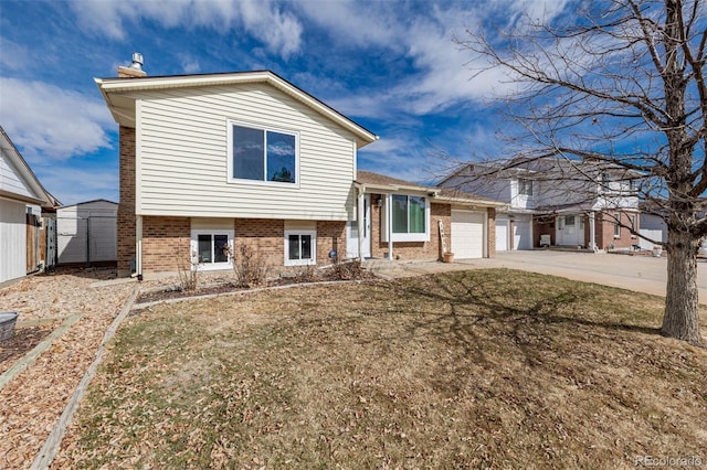 tri-level home with brick siding, a front yard, fence, a garage, and driveway