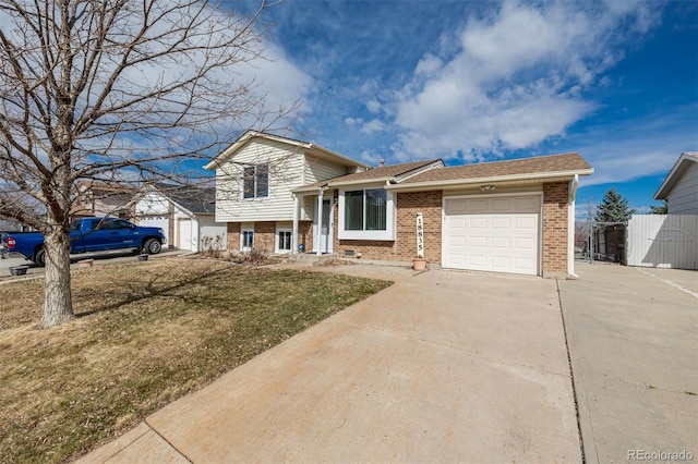 tri-level home featuring a garage, brick siding, concrete driveway, fence, and a front yard