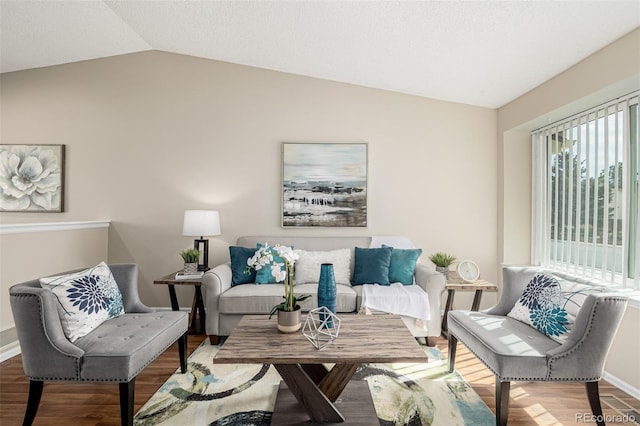 living area featuring vaulted ceiling, baseboards, and wood finished floors