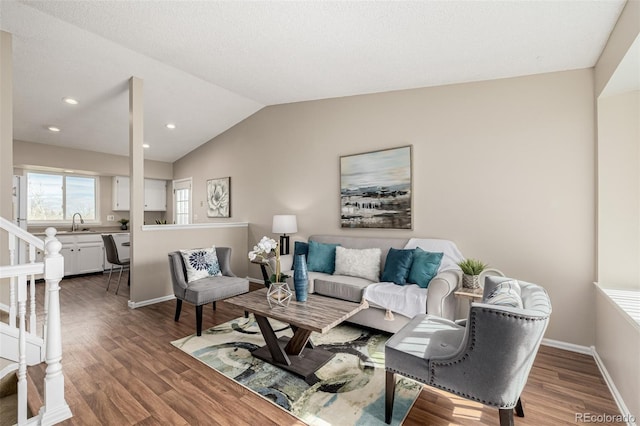 living area featuring stairway, baseboards, vaulted ceiling, and wood finished floors