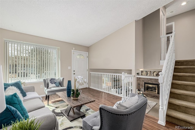 living area featuring stairway, lofted ceiling, a textured ceiling, and wood finished floors