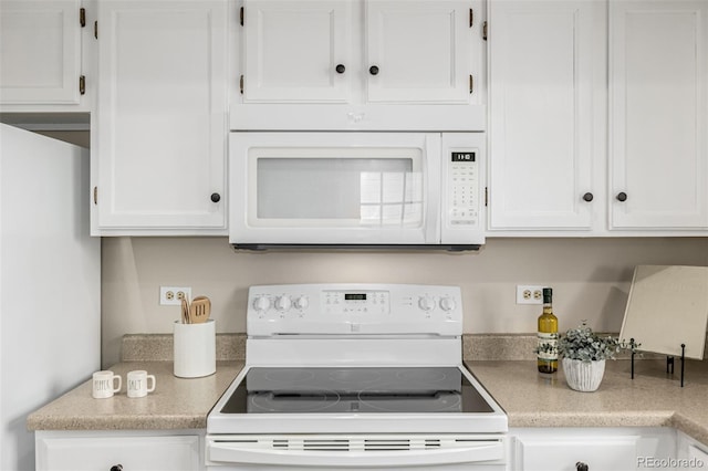 kitchen featuring light countertops, white appliances, and white cabinetry