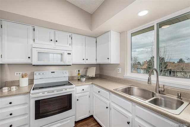 kitchen with white appliances, white cabinets, dark wood-style flooring, light countertops, and a sink