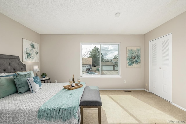 bedroom with a textured ceiling, carpet floors, visible vents, and baseboards