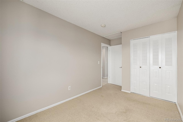 unfurnished bedroom featuring light carpet, a textured ceiling, baseboards, and a closet