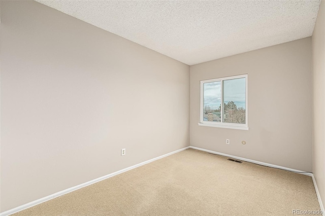 carpeted empty room featuring visible vents, a textured ceiling, and baseboards