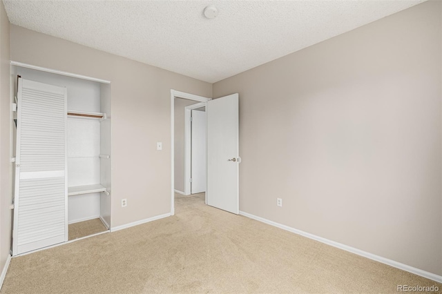 unfurnished bedroom featuring a closet, carpet flooring, a textured ceiling, and baseboards