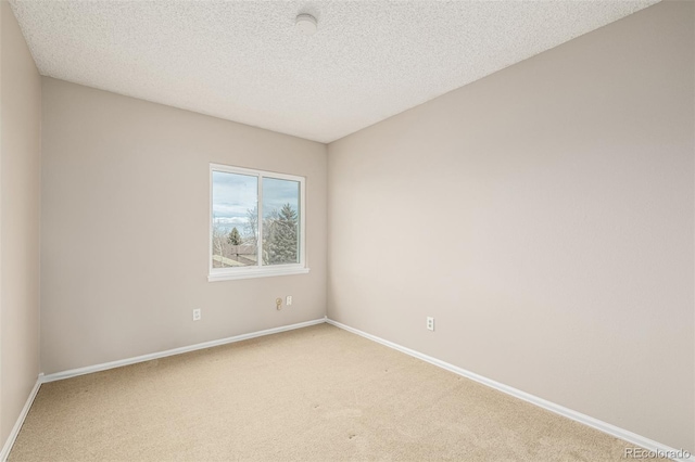 empty room featuring baseboards, a textured ceiling, and light colored carpet