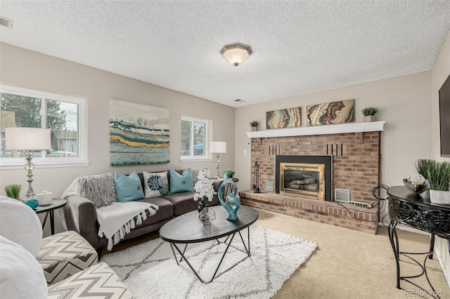 living room featuring a brick fireplace, visible vents, a textured ceiling, and carpet flooring