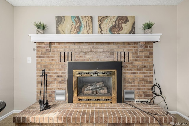 interior details featuring carpet, a textured ceiling, a fireplace, and visible vents