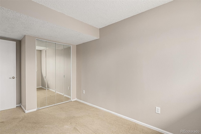 unfurnished bedroom featuring carpet, a closet, baseboards, and a textured ceiling