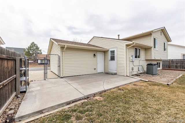 rear view of property with a patio, central AC unit, fence, a yard, and a gate