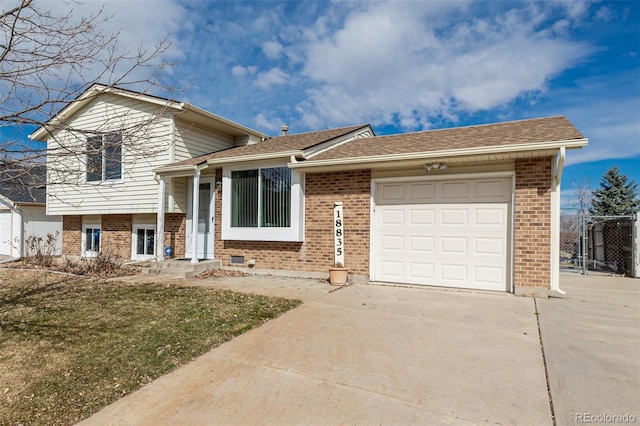 split level home with a garage, concrete driveway, and brick siding