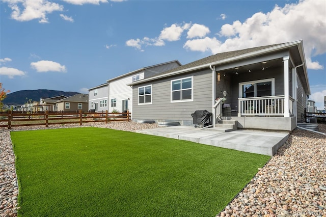 rear view of house featuring a mountain view, fence, a lawn, and a patio