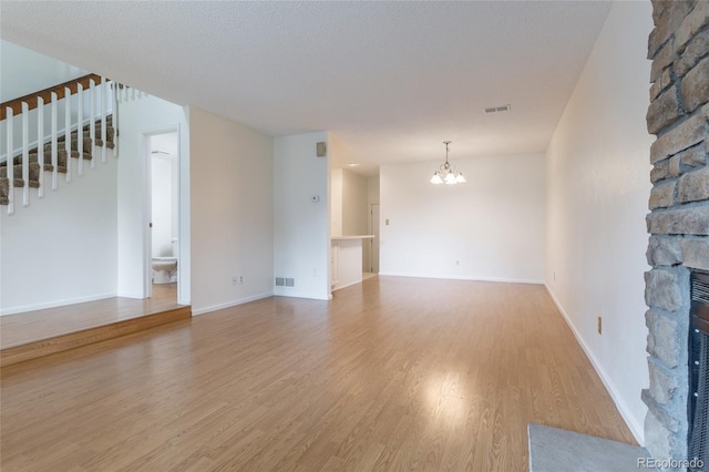 8463 Everett Way Unit B, Arvada, CO 80005 - unfurnished living room with stairs, a fireplace, light wood-type flooring, and a chandelier