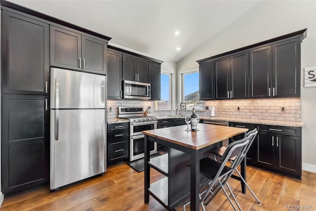 255 Flannigan Cir, Alma, CO 80420 - kitchen featuring tasteful backsplash, vaulted ceiling, light stone counters, dark cabinets, and stainless steel appliances