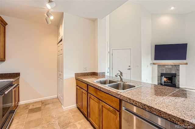 kitchen featuring a sink, stainless steel appliances, tile countertops, brown cabinets, and rail lighting