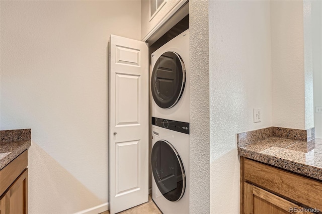washroom featuring stacked washer and clothes dryer and a textured wall