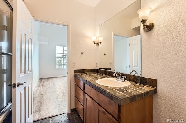 bathroom with vanity, wood finished floors, and a textured wall