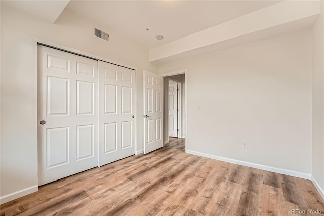 unfurnished bedroom featuring wood finished floors, baseboards, and a closet