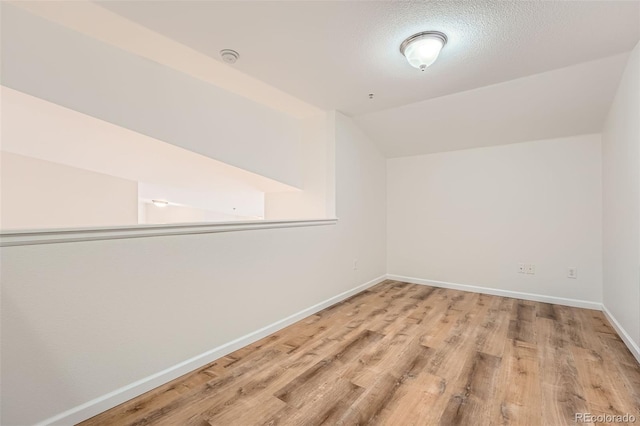 bonus room featuring vaulted ceiling, wood finished floors, baseboards, and a textured ceiling