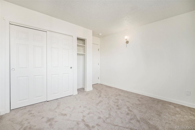 unfurnished bedroom with light colored carpet, a closet, and a textured ceiling