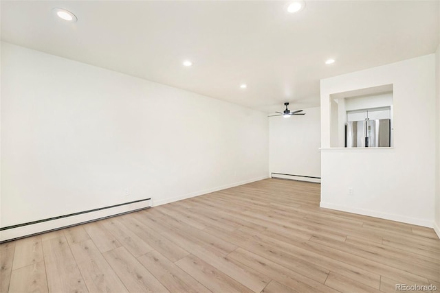 spare room featuring ceiling fan, light hardwood / wood-style floors, and a baseboard heating unit