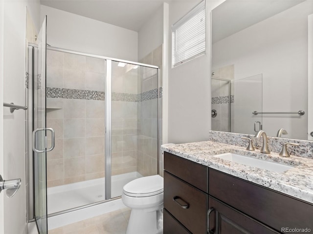 bathroom featuring toilet, tile patterned flooring, an enclosed shower, and vanity