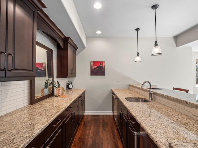 kitchen featuring hanging light fixtures, sink, light stone counters, and dark hardwood / wood-style floors