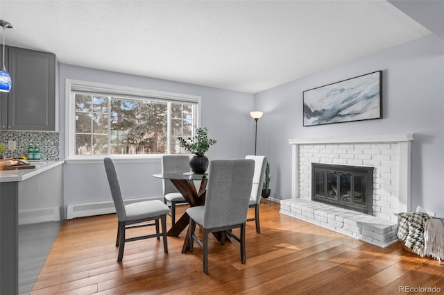 dining room with light wood-type flooring and a brick fireplace