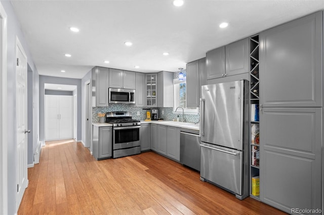 kitchen with light hardwood / wood-style floors, sink, gray cabinets, and stainless steel appliances