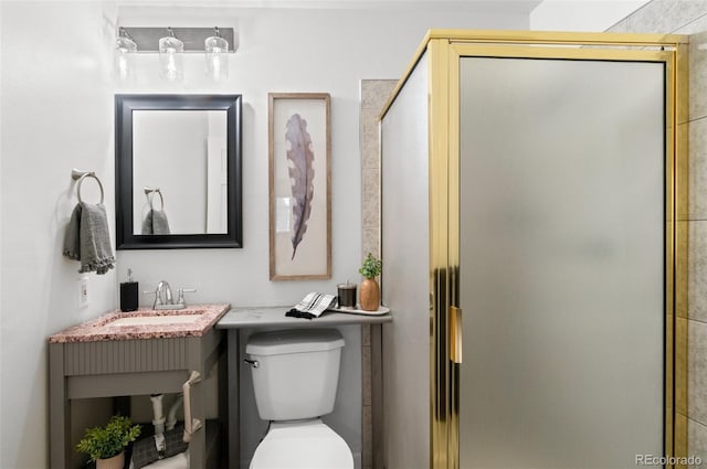 bathroom featuring toilet, a shower with door, and vanity