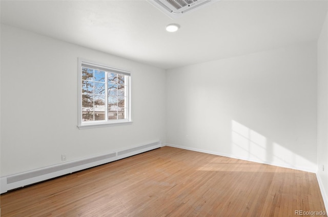 empty room featuring hardwood / wood-style floors and baseboard heating