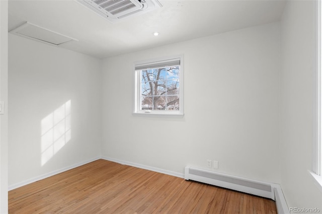 empty room featuring light wood-type flooring and a baseboard heating unit