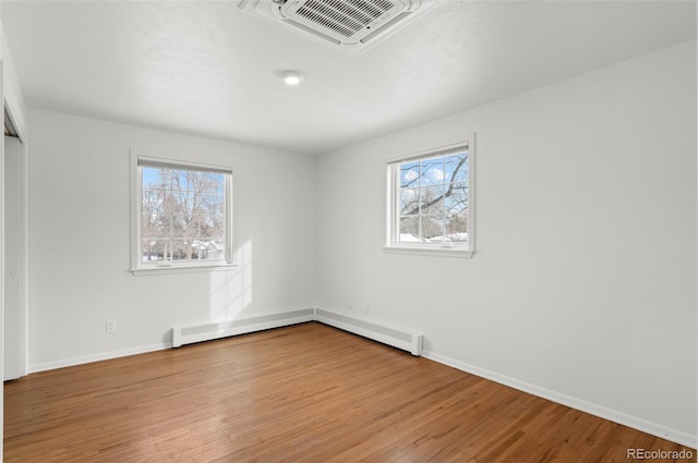 empty room with baseboard heating and light wood-type flooring