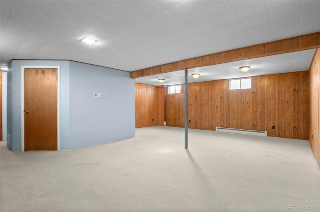 basement with a baseboard radiator, light colored carpet, and wood walls