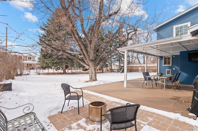 snow covered patio with a wooden deck