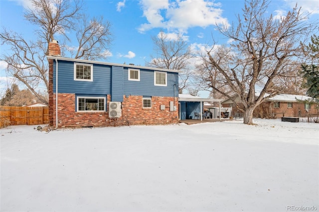 snow covered rear of property featuring ac unit