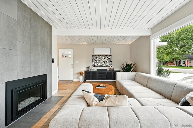1440 S Clermont St, Denver, CO 80222 - living room featuring light wood-style flooring, wood ceiling with exposed beams, a tile fireplace, and baseboards