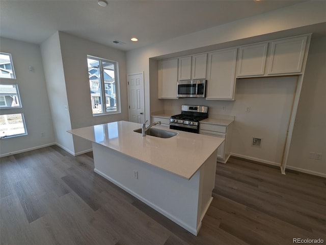 kitchen with dark hardwood / wood-style floors, stainless steel appliances, a kitchen island with sink, and sink