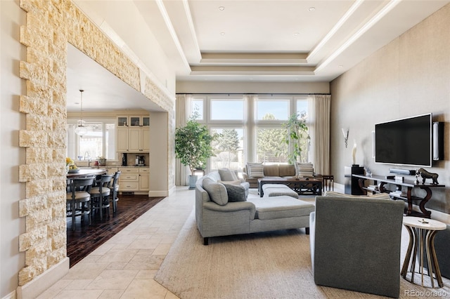 living area featuring a raised ceiling and stone tile flooring