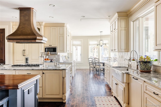 kitchen featuring cream cabinets, appliances with stainless steel finishes, island range hood, and a sink